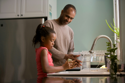 A girl doing the dishes while the man supervise 